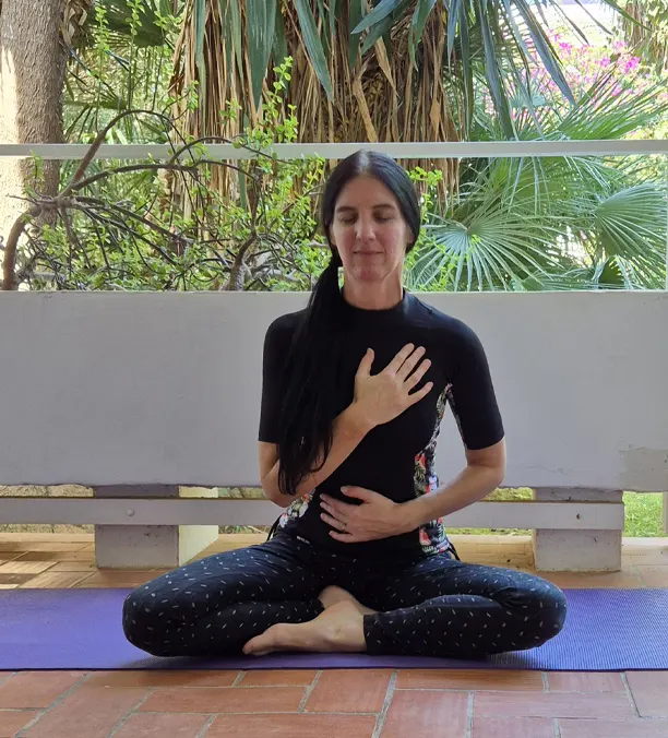 Mujer meditando en una terraza rodeada de naturaleza, simbolizando Yoga como Estilo de Vida.